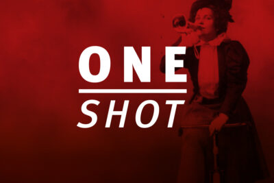 Logo 'ONE SHOT' in weißer Schrift auf rotem Hintergrund. Im Hintergrund ist schemenhaft eine Tänzerin in Bewegung zu erkennen. 'ONE' steht in Großbuchstaben über einem horizontalen Strich, darunter 'SHOT' in kursiver Schrift.