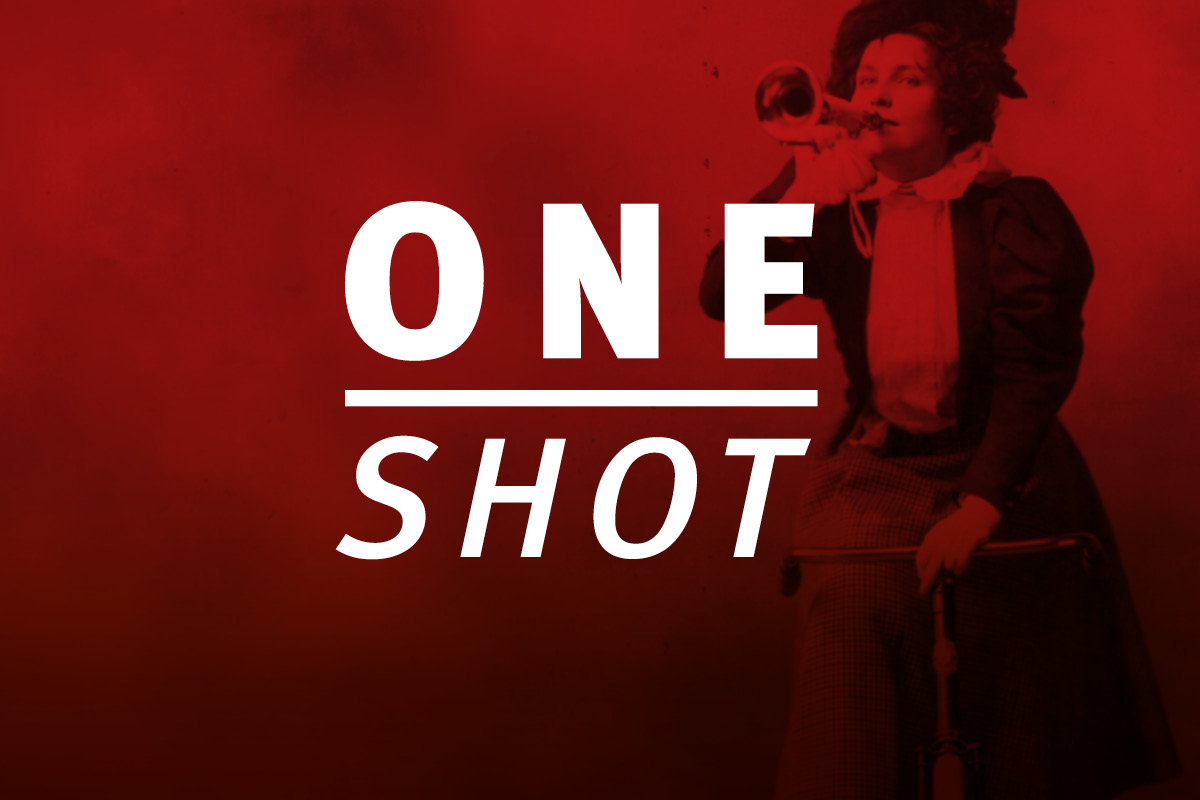 Logo 'ONE SHOT' in weißer Schrift auf rotem Hintergrund. Im Hintergrund ist schemenhaft eine Tänzerin in Bewegung zu erkennen. 'ONE' steht in Großbuchstaben über einem horizontalen Strich, darunter 'SHOT' in kursiver Schrift.