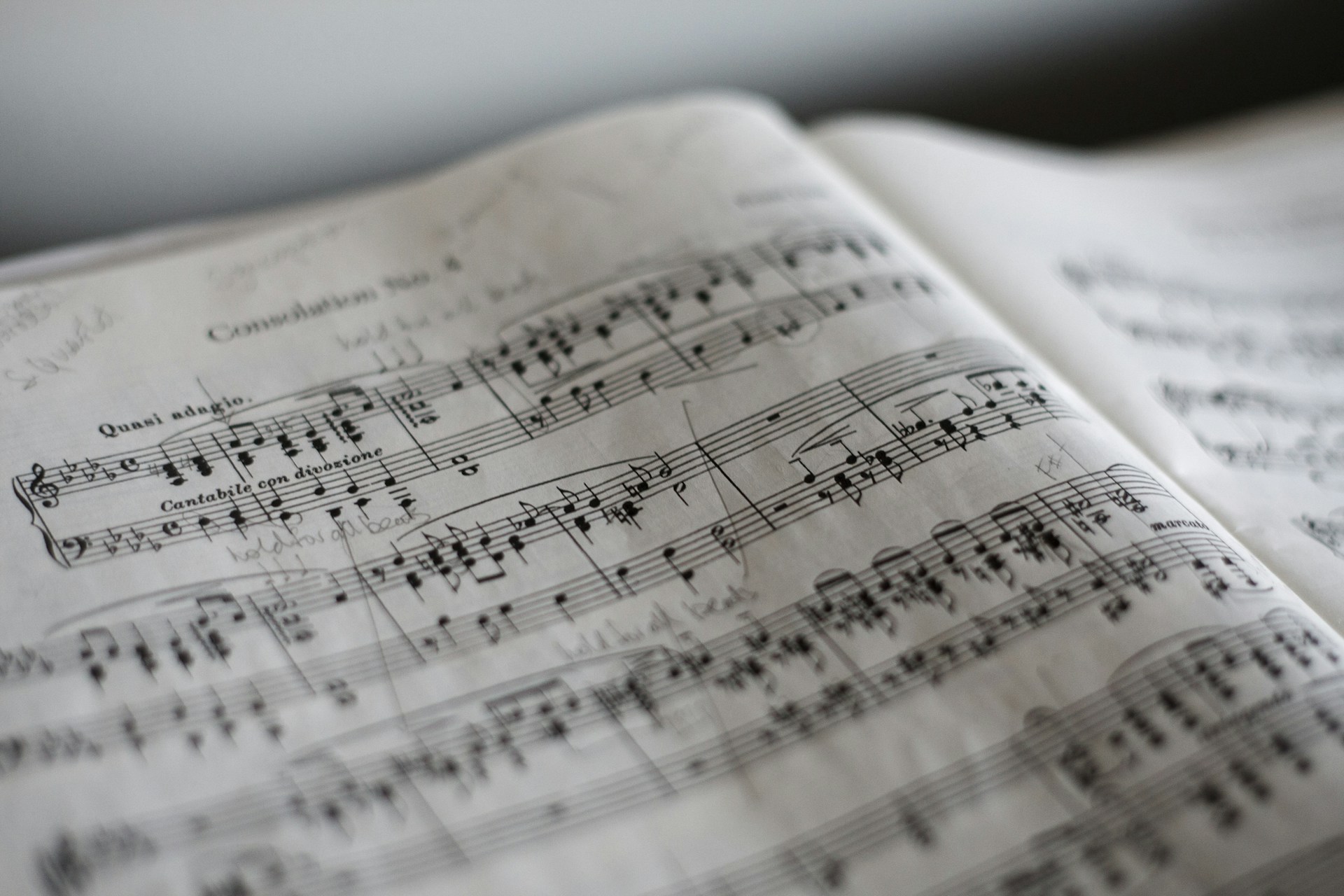 Nahaufnahme eines aufgeschlagenen Notenbuchs mit handschriftlichen Anmerkungen. Die Notenlinien und musikalischen Symbole sind deutlich sichtbar, während der Hintergrund leicht unscharf ist.