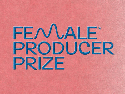 Logo des „Female* Producer Prize“ in blauer Schrift auf rotem Hintergrund; das Wort „Female“ enthält ein stilisiertes M in Form einer Wellenlinie, das Gendersternchen steht rechts oben am Wortende.