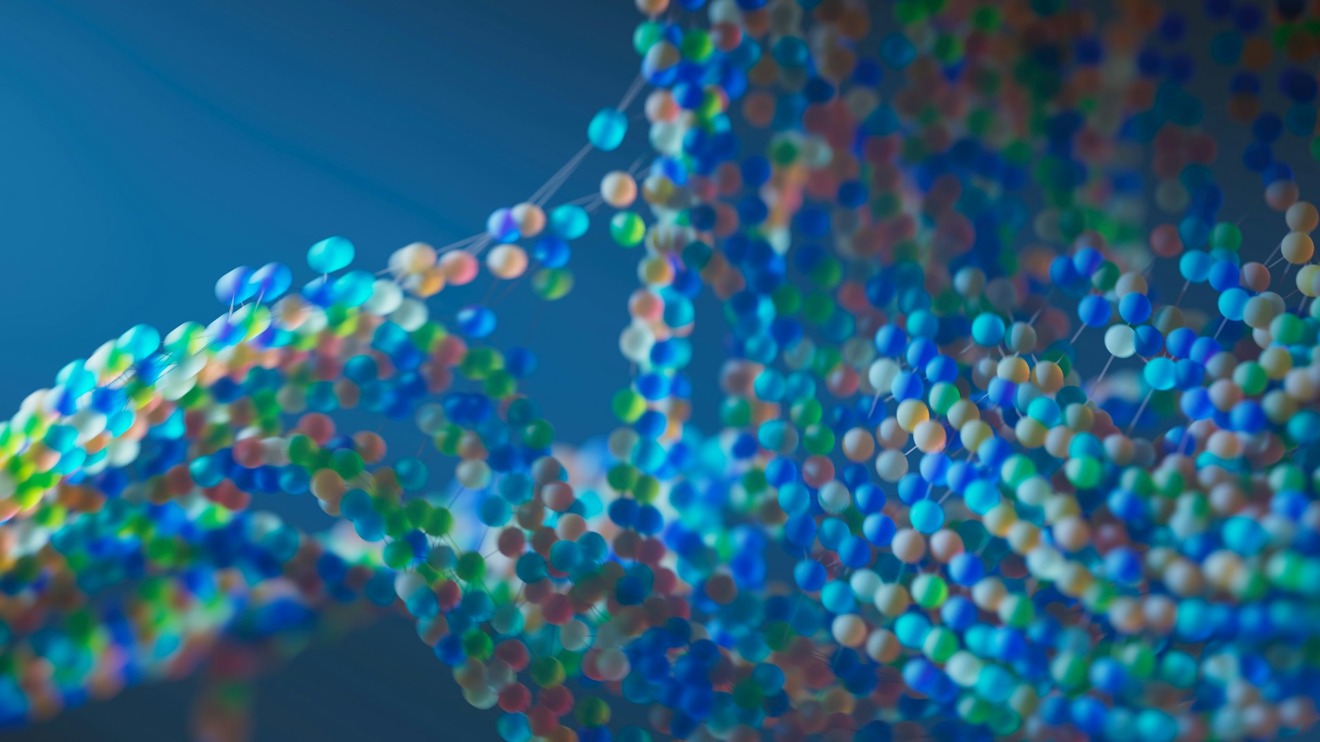 Bunte, unscharf dargestellte Molekülstruktur auf blauem Hintergrund; zahlreiche kleine, farbige Kugeln sind durch dünne Verbindungen zu einem komplexen, netzartigen Muster verbunden, das an eine DNA-Doppelhelix erinnert.