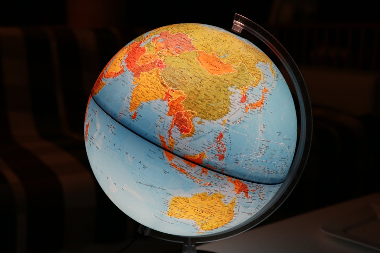 Ein beleuchteter Globus mit Fokus auf Asien, Australien und dem Indischen Ozean. Der Globus steht in einem dunklen Raum auf einem Tisch, im Hintergrund ist ein gestreiftes Sofa zu erkennen.