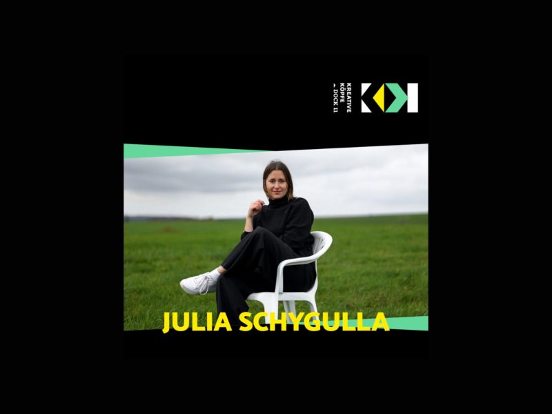 Ein Foto von Julia Schygulla auf einem Monobloc auf grüner Wiese sitzend.