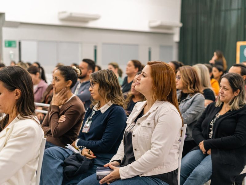 ine Gruppe von Teilnehmer:innen sitzt aufmerksam in einem Konferenzraum. Die Stimmung ist konzentriert, während die Zuhörer einem Vortrag folgen. Vorne sitzen überwiegend Frauen, die sich aktiv an der Veranstaltung beteiligen.