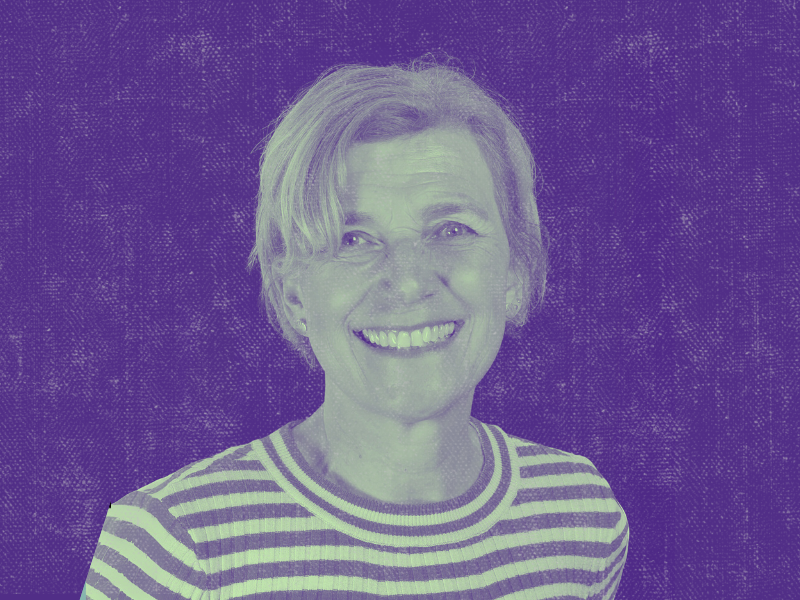 Porträt einer älteren Frau mit kurzem, blondem Haar, die in die Kamera lächelt. Sie trägt ein gestreiftes Shirt. Das Bild ist in einem lila-grünen Duoton-Effekt gehalten, der Hintergrund ist texturiert und dunkel.