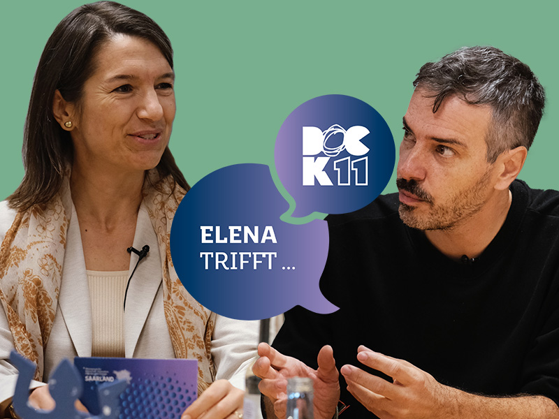 Zwei Personen sitzen an einem Tisch und unterhalten sich. Links eine Frau, die lächelt, rechts ein Mann, der aufmerksam zuhört und gestikuliert. Zwischen ihnen sind zwei Sprechblasen mit den Texten „ELENA TRIFFT …“ und „DOCK 11“.