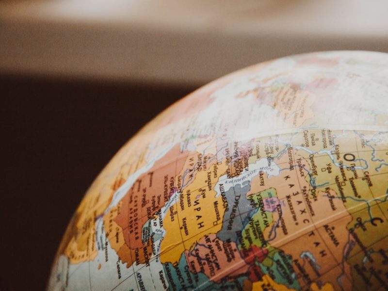 Nahaufnahme eines Globus, der Teile von Europa, dem Nahen Osten und Zentralasien zeigt, darunter Länder wie Iran, Russland und Kasachstan, in warmen Farbtönen beleuchtet.