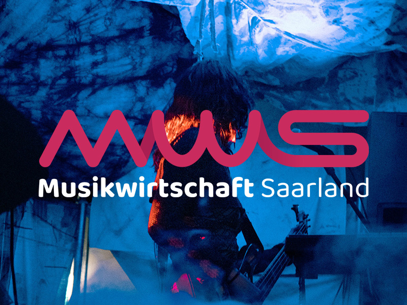 Auf dem Bild ist das Logo der Musikwirtschaft Saarland prominent über eine atmosphärische Liveszene gelegt. Im Hintergrund steht eine Musikerin oder ein Musiker auf einer Bühne, umgeben von intensivem blauem und violettem Licht, das eine fast traumartige Stimmung erzeugt. Stoffbahnen oder projizierte Muster hängen über der Szene und verstärken den künstlerischen Charakter. Im Vordergrund dominiert das magentafarbene MWS-Logo mit seiner weichen, wellenartigen Linienführung, darunter in weißer Schrift der Schriftzug „Musikwirtschaft Saarland“. Die Kombination aus lebendiger Konzertstimmung und klarer, moderner Logogestaltung vermittelt dynamisch, kreativ und professionell die Identität der musikalischen Szene im Saarland.